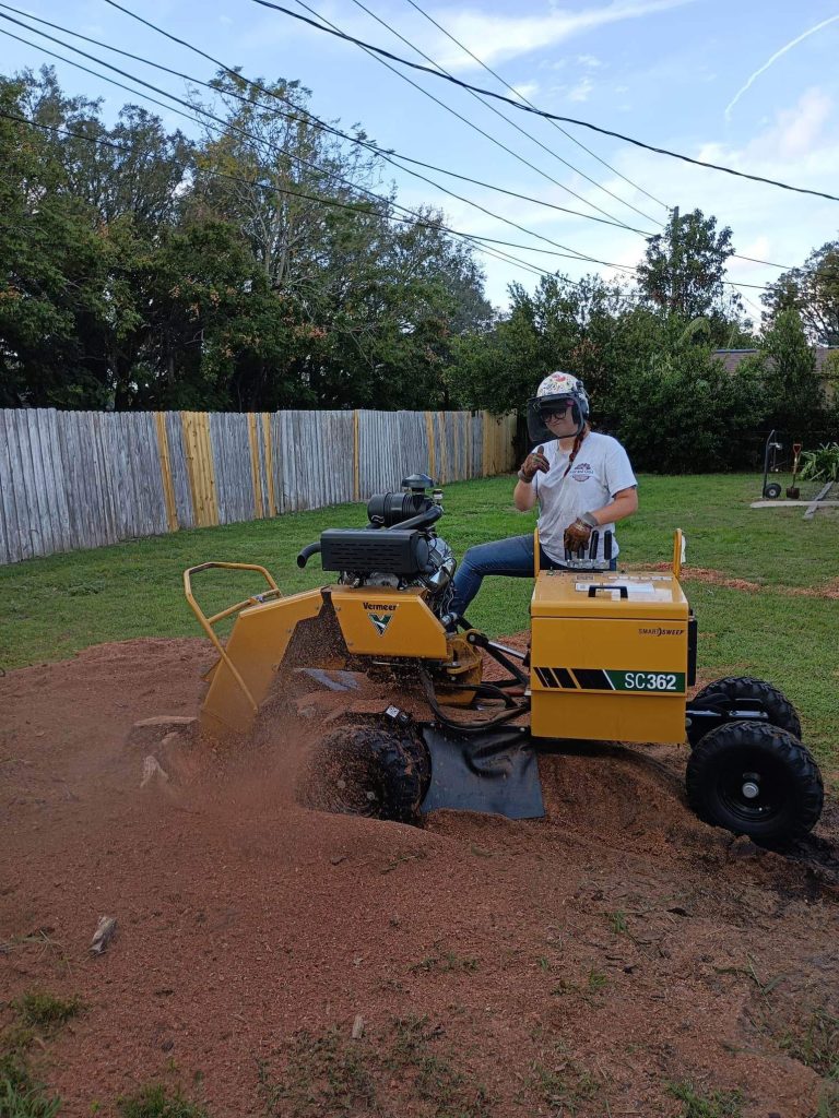 Female grinding stumps in a yard.